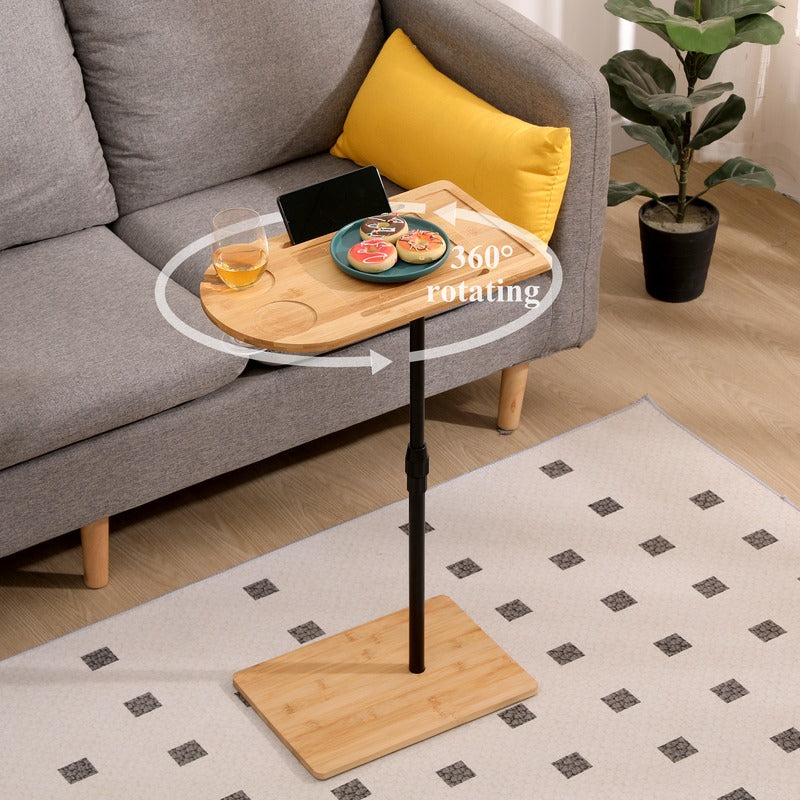 Adjustable bamboo sofa tray table beside a couch with snacks and drinks